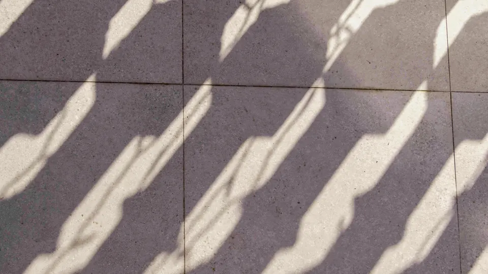 Sombras de luz natural proyectadas en diagonal sobre un pavimento de baldosas claras