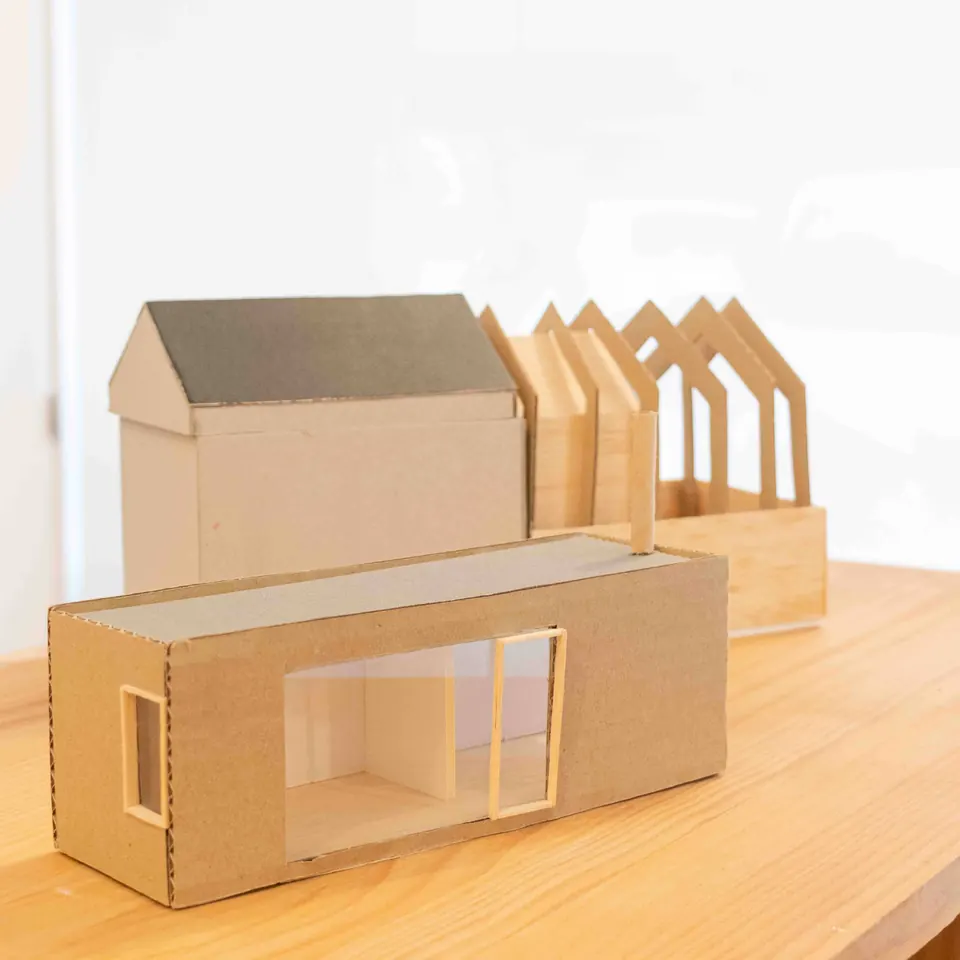 Maquetas de cartón y madera de varias viviendas sobre una mesa del estudio