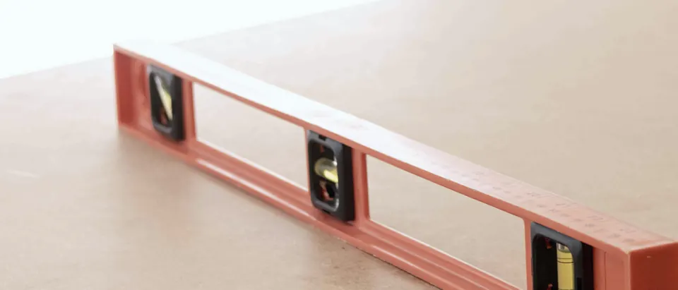 Nivel de burbuja naranja apoyado sobre un tablero de madera
